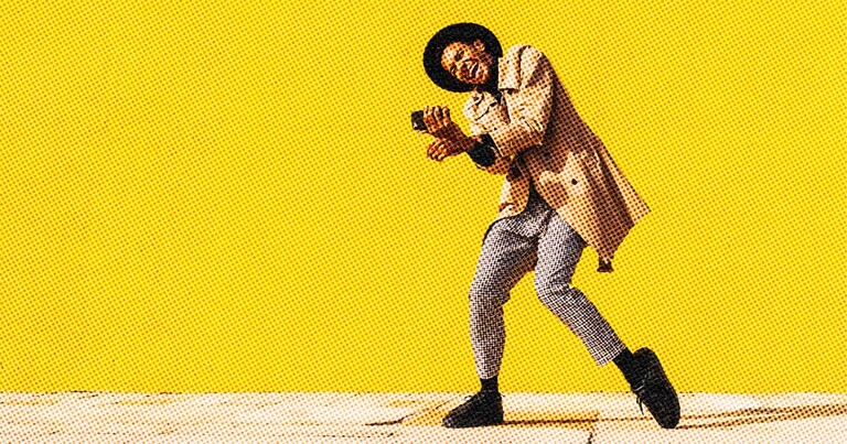 Person dances with their phone in hand against a yellow wall.